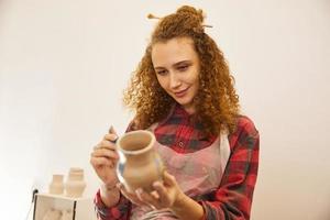 Pretty curly girl paints a vase before baking photo