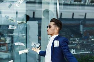 Dollars fly around handsome young businessman photo