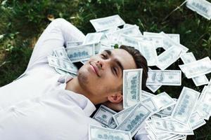 Man lying in the grass with hundred dollar bills photo