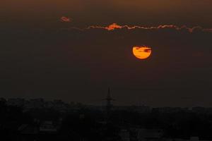 Sun behind clouds at sunset photo