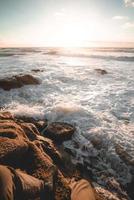 Person sitting on rock beside beach photo