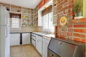 Old simple white kitchen with brick wall.