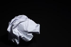 Crumpled paper on black background photo