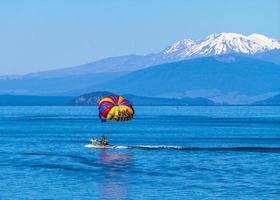 lago taupo, nueva zelanda, 2020: un grupo de parasailing montado en un bote cerca de las montañas foto