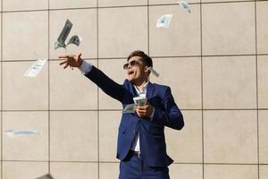 Young businessman throws around dollars and dances on the street photo