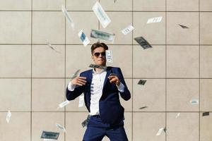 Young businessman throws around dollars and dances on the street photo