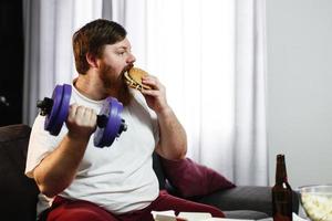 Man eating a hamburger while lifting weights photo