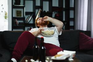 Man eating popcorn on the sofa photo