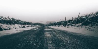 Grayscale of a road surrounded by snow photo