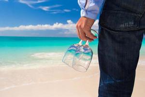 Close-up of a person holding glasses on a beach photo