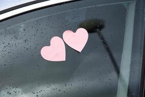 Two heart shaped post-it on a car window with raindrops photo