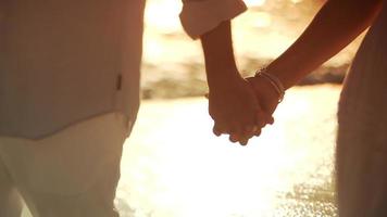 casal caminhando de mãos dadas na praia