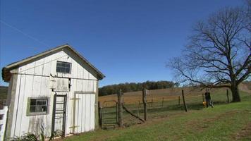 White barn and tractor in field video