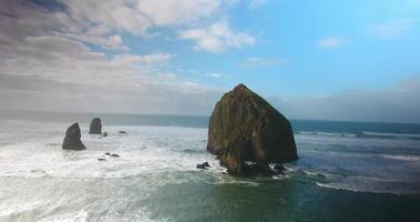 Drone Flyover Haystack Rock in Bright Blue Ocean Water  video