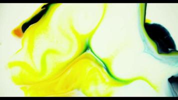 Yellow and green paint mixing to create random shapes on white surface video