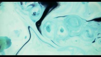 Blue paint mixing on white paint surface creating strange rounded shapes video