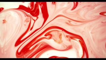 Red paint moving on white paint surface creating organic shapes and swirls in 4K video