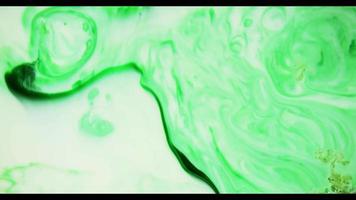 Green paint moving on white surface creating an organic texture of swirls in 4K video