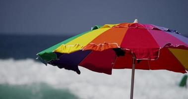 Static shot of a colorful umbrella with sea waves in the background in 4K video