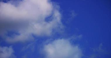 lapso de tempo de nuvens cúmulos suaves e brilhantes girando sobre fundo azul em 4k video