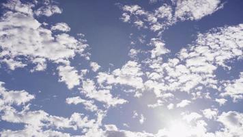 time-lapse van verschillende groepen altocumulus wolken bewegen op blauwe hemel met zonlicht fakkels in 4k video