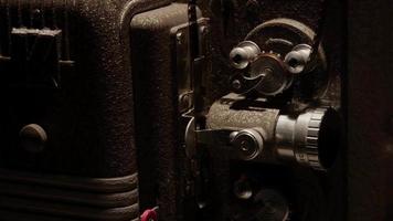 Close up of 8mm movie projector mechanism and film moving on the rollers in 4K video