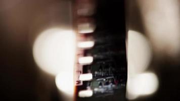 Primer plano frontal extremo del proyector de películas de 8 mm y detalle de las ruedas dentadas y fotogramas de la película en 4k video