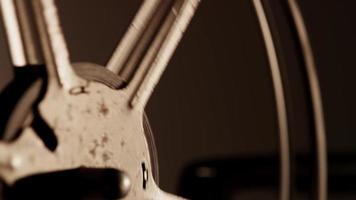 Extreme close up of 8mm movie projector, showing a detail of a rusty reel unrolling film in 4K video