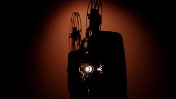 drie quaerterweergave van een silhouet van een persoon die een 8 mm-filmprojector aan- en uitzet met spoelen die in 4k draaien video