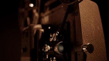 Three quaerter view of a 8mm movie projector working and flashing with film moving and reels spinning in 4K video