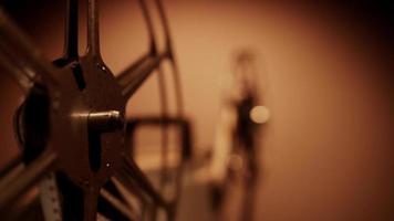 Extreme close up of film reels spinning on projector with focus in foreground and warm background in 4K video