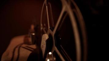 Extreme close up of film rolling and unrolling on rusty reels with warm illumination in 4K video