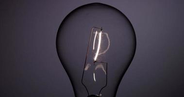 Close up of classic light bulb turning on and off with vertical filament in 4K video