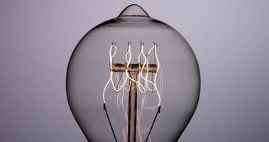 Nahaufnahme der Vintage Glühbirne, die sich einschaltet und mit Federfaden in 4k ausschaltet
