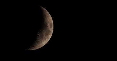 Waxing crescent moon moving slowly from left to right of the scene with sepia filter in 4K video