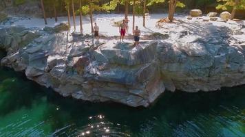 Drone shot of people cliff jumping into a swimming hole | Free Stock Footage