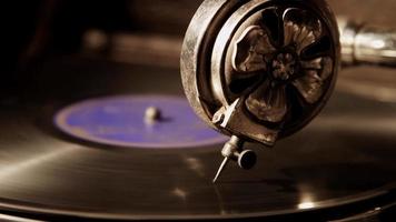 Extreme close up shot with light from left side of record player, focusing in a decorated reproducer needle playing a vinyl disc in 4K video