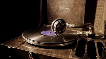 Medium static shot of classic record player and old vinyl disc spinning with overhead lighting in 4K video