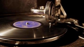 Dark medium shot of record player with vinyl disc illuminated from left side of the scene in 4K video