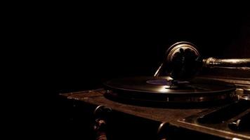  Dark traveling shot from left to right of classic record player working with soft overhead lighting in 4K video