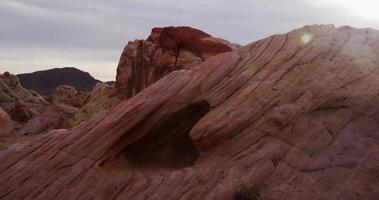 Toma panorámica que va a la izquierda de rocas rojas, colinas y montañas lejanas en un paisaje desértico en 4k video