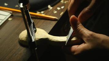 Close-up hands carving wooden spoon with clamp, warm light | Free Stock Footage video