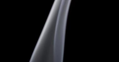 White delicate column of controlled smoke dancing on dark background in 4K video