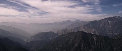 Time lapse of clouds moving from left to right on mountain range with blue sky in background in 4K video