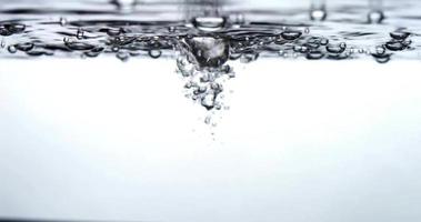 riempire un contenitore con liquido chiaro che spruzza nella superficie dell'acqua con piccole e grandi bolle in 4K video