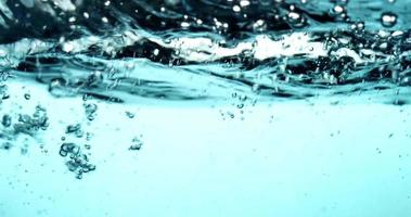 Blue scene of water splashing from right to left creating little bubbles in 4K video