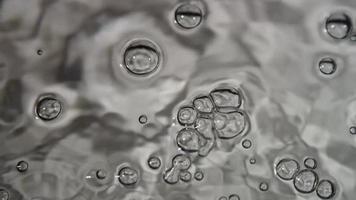 Monochromatic scene of aquarium bubbles moving on water surface with waves in 4K video
