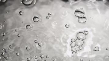 Monochromatic scene of little bubbles moving from lower to upper section of the scene on water surface in 4K video