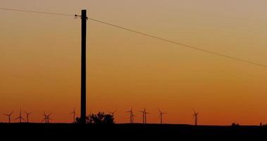 Extreme long shot of wind farm with fifteen eolic generators on sunset background in 4K