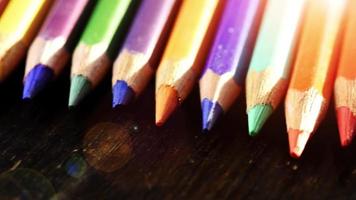 On a wooden background multi-colored pencils. Bright colored pencils Close up. Macro. Macro shooting video